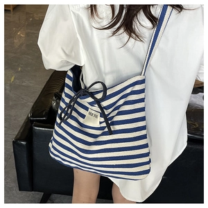 Detail of blue striped canvas tote bag with bow tie and SEE YOU woven label