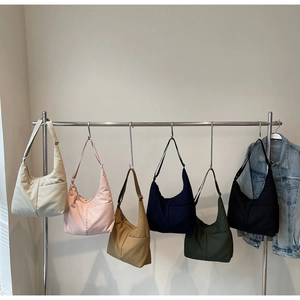 Detail of minimalist nylon crescent tote bags in six colors hanging on a rack