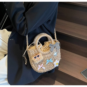 Détail du sac panier en paille avec ourson en peluche et nœuds sur escalier en bois
