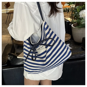 Detail of blue striped canvas tote bag with decorative rope bow and textile label