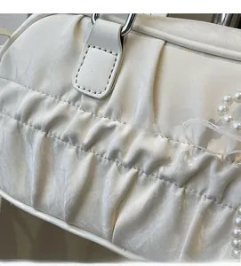 Detail shot of white pleated handbag with glossy fabric and decorative pearl chain link