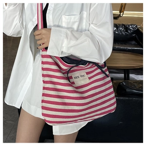 Detail shot of a large pink striped canvas tote bag with 'SEE YOU' patch on model