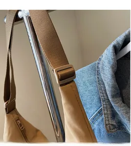 Detail of adjustable woven shoulder strap and buckle on khaki nylon tote bag