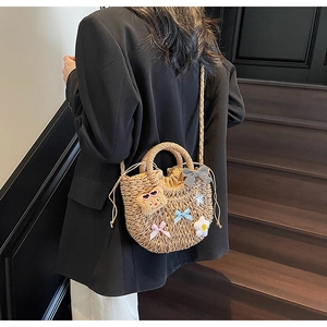 Détail d'un sac en paille tissé à la main avec pendentif ours et fleurs blanches