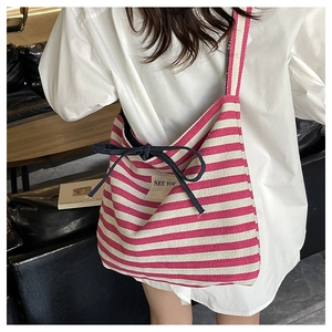 Detail of pink striped canvas tote bag with navy bow and white SEE YOU patch on model