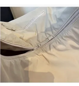 Dettaglio macro della chiusura a cerniera in tinta su una borsa tote in tela beige