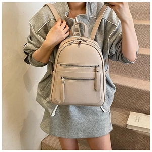 Beige lychee leather backpack detail showing metal zippers and adjustable straps