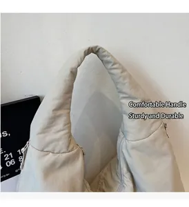 Dettaglio di una borsa tote beige con manici rinforzati e trama in nylon trapuntato