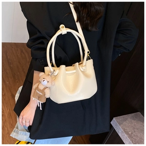 Detail of cream pleated bucket bag with bear charm and detachable leather strap