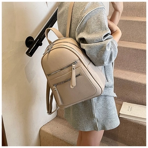 Close-up of beige lychee texture backpack with multiple zippers on model back