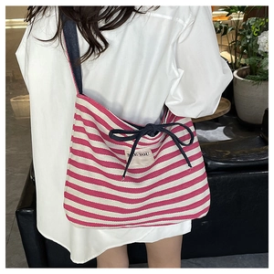 Detail of pink striped canvas tote bag featuring navy drawstring bow and See You label
