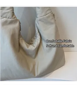Dettaglio della borsa tote beige che mostra il tessuto morbido e la tracolla larga