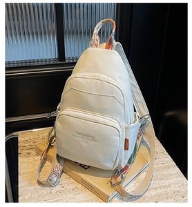 Detail of white multi-functional chest bag featuring colorful ethnic woven shoulder strap