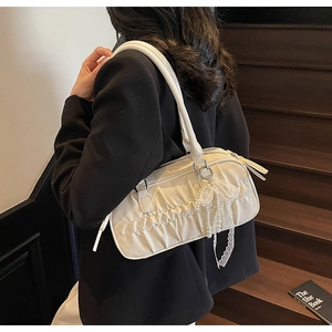 White ruched shoulder bag with pearl bow pendant detail shown on model against stairs
