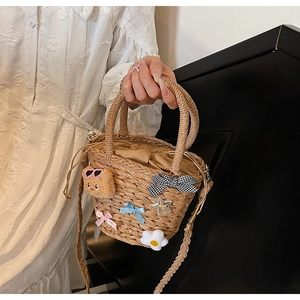 Détail du sac de plage tressé avec charms ours et fermeture par cordon de serrage