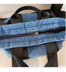 Détail de la fermeture éclair en métal sur un sac cabas en denim avec poignées en tissu