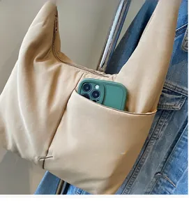 Close-up of the durable side pocket on the beige nylon tote bag with a smartphone inside