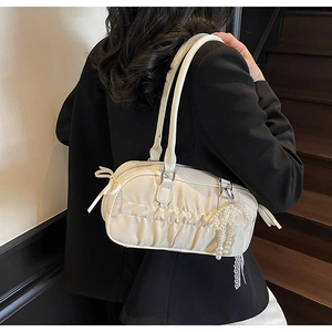 Detail of cream pleated handbag with decorative silk bow and pearl lace pendant