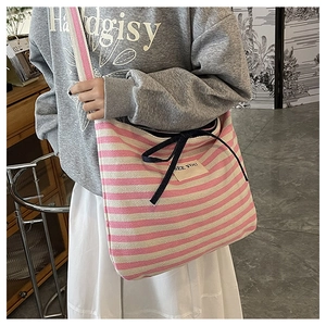 Detail of pink striped canvas tote bag featuring navy bow closure and see you patch