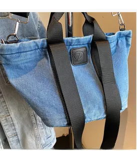 Détail du grand sac cabas en denim avec poignée en sangle noire et logo carré