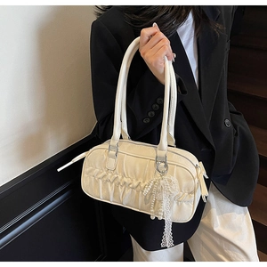 Close-up of cream pleated bowling bag featuring a white pearl and lace floral charm