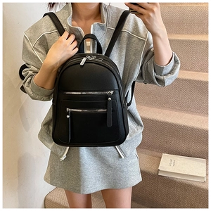 Detail of black lychee-grain leather backpack with silver zippers on a casual model