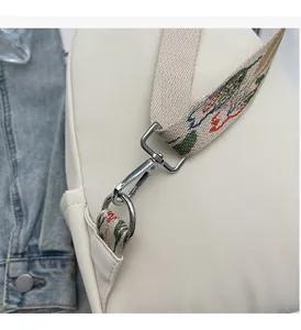 Detailed macro view of silver metal hooks and colorful woven strap on a white bag
