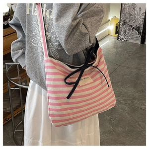 Detail of pink and white striped canvas tote bag with black drawstring bow and SEE YOU tag