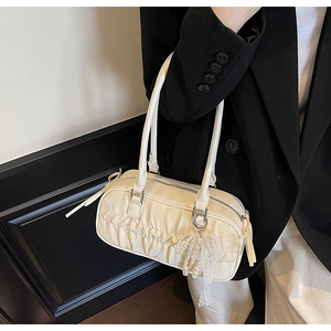 Detail of ruched beige shoulder bag with pearl charm and lace bow on a model