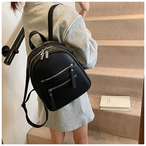 Detailed view of black pebble leather backpack with silver zippers on a model