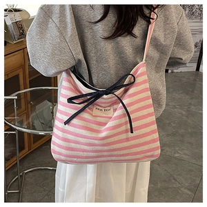 Detail of pink and white striped canvas tote with a blue bow and SEE YOU patch decoration