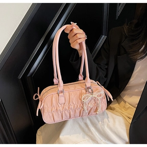 Close-up of pink ruched bowling bag with pearl bow charm and elegant long handles