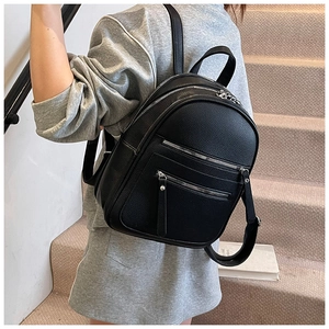 Detail of black pebbled leather backpack showing silver zippers and front pockets