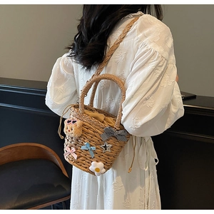 Détail d'un sac seau en paille tissé main avec ours mignon et rubans décoratifs