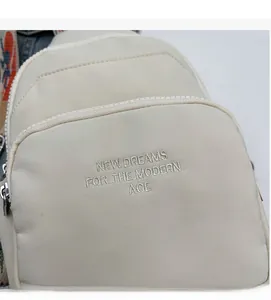 Detail of off-white chest bag featuring embroidered text and silver metal zipper