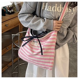 Close-up of pink striped canvas tote bag featuring a blue bow and SEE YOU label detail