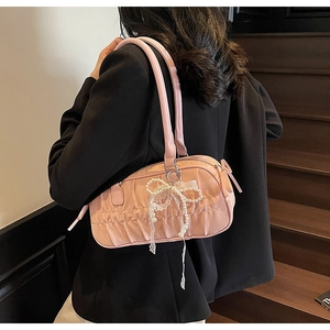 Detail of pink pleated shoulder bag with pearl accents and bow charm on a model