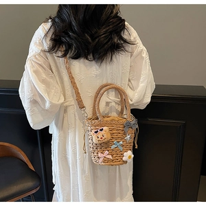 Détail du sac seau en paille avec ours en peluche mignon et nœuds en ruban