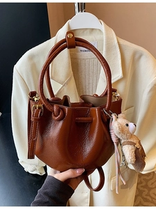 Dark brown pleated bucket bag in glossy PU leather with bear charm and top handle