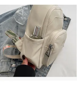 Close-up of off-white chest bag side pocket showing capacity with perfume bottle
