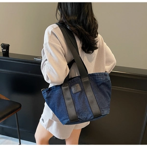 Détail du sac cabas en jean bleu marine avec sangles en nylon porté par le mannequin