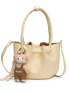Cream pleated bucket bag with plush bear charm and adjustable crossbody strap