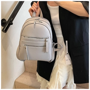 Close-up of light grey faux leather backpack featuring multi-layer zipper compartments