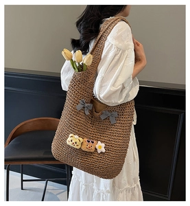 Détail d'un sac cabas en paille tressée avec nœuds et pendentifs ours en peluche