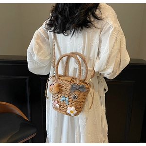 Détail du sac en paille avec ours 3D, nœuds colorés et fermeture à cordon sécurisée