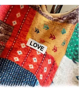 Detailopname van de boho patchwork draagtas met kleurrijke patronen en LOVE-weblabel