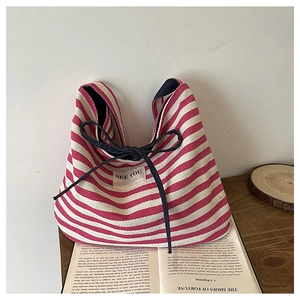 Detail of red and white striped canvas tote bag with black drawstring and textile patch
