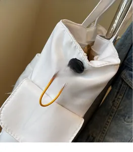 Detail of white canvas bag featuring yellow elastic drawstrings and black toggle stoppers