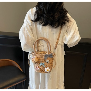 Détail du sac bandoulière en paille tressé avec des écussons ours et fleurs mignons