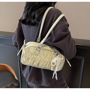 Close-up of light green pleated shoulder bag featuring a pearl lace bow charm detail